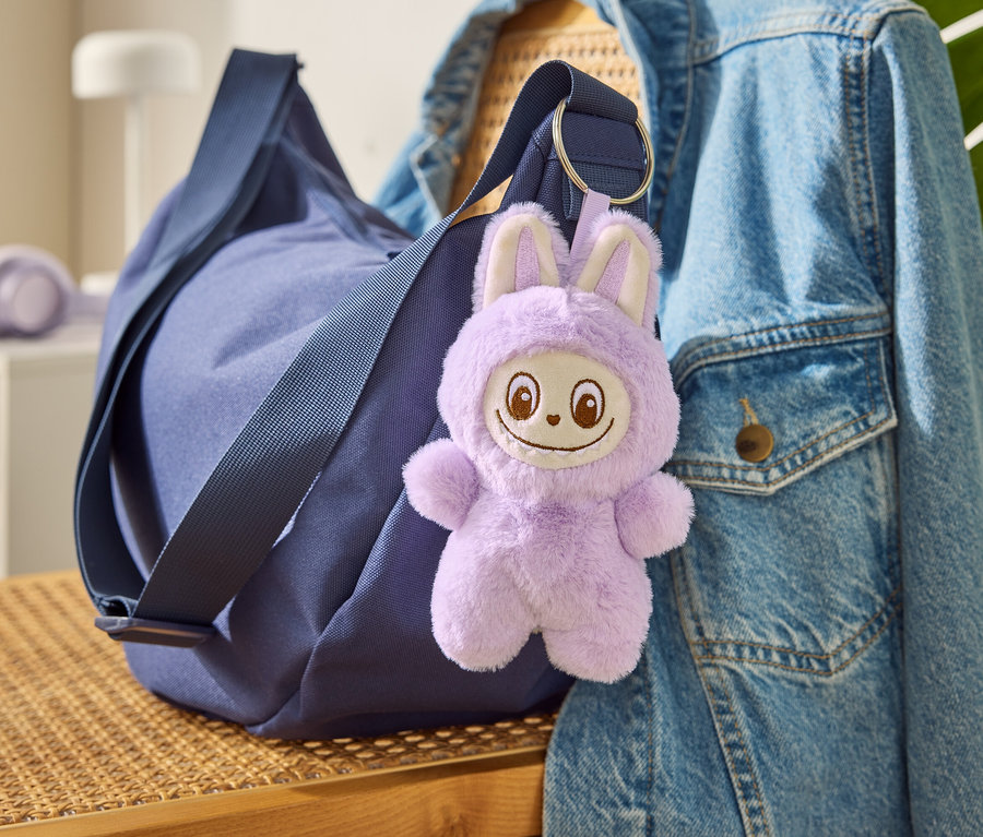 Eine blaue Tasche mit dem Schlüsselanhänger »Tchibobo« hängt an einer Jeansjacke.