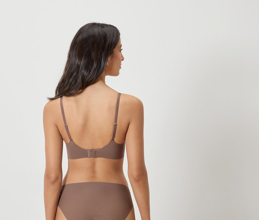 Rückansicht einer Frau mit dunklen Haaren, die einen braunen BH und Unterwäsche trägt.