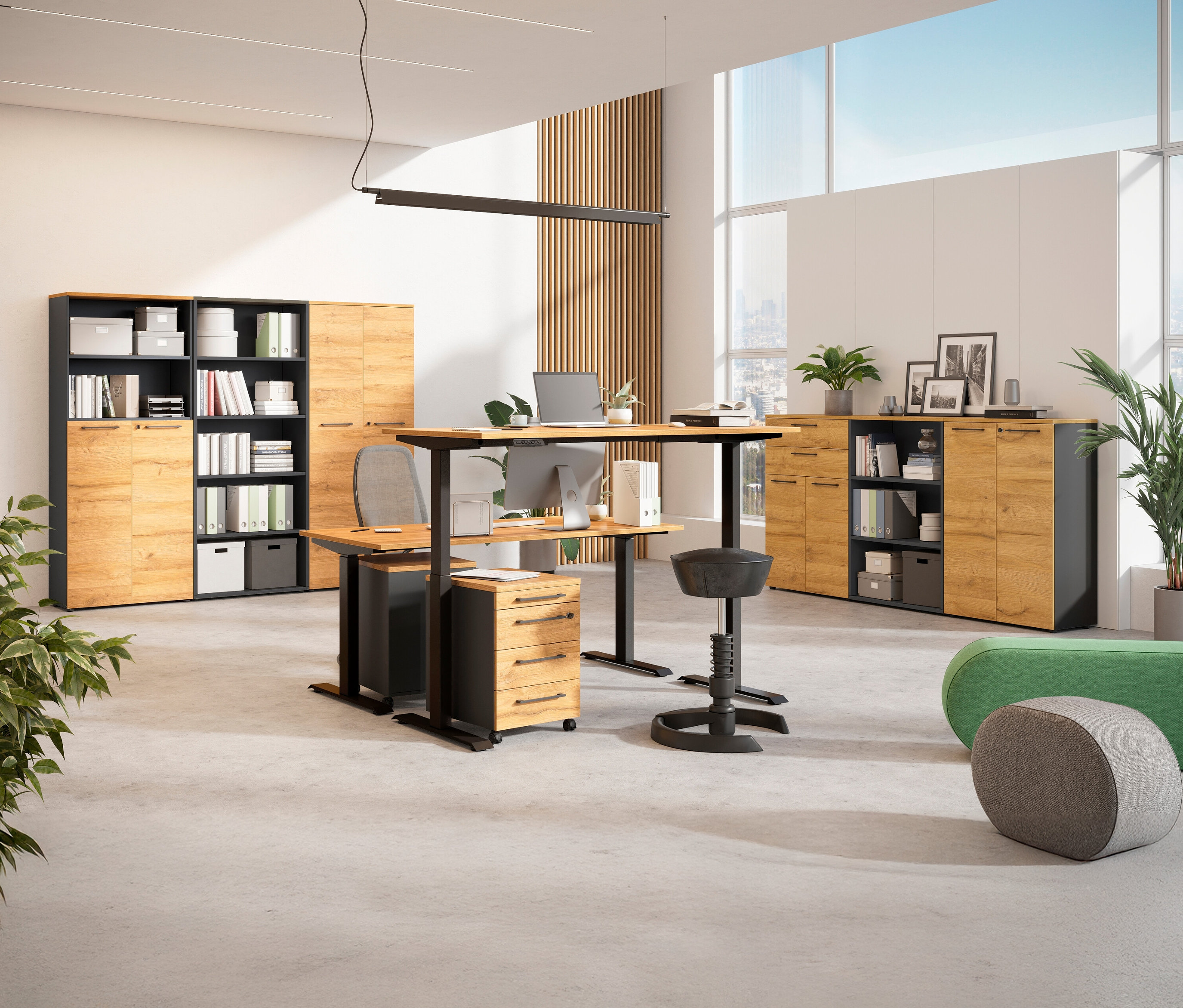 Ein Büroraum mit einem elektrisch höhenverstellbaren Schreibtisch (Breite ca. 180 cm), Regalen und einem Stehhocker.