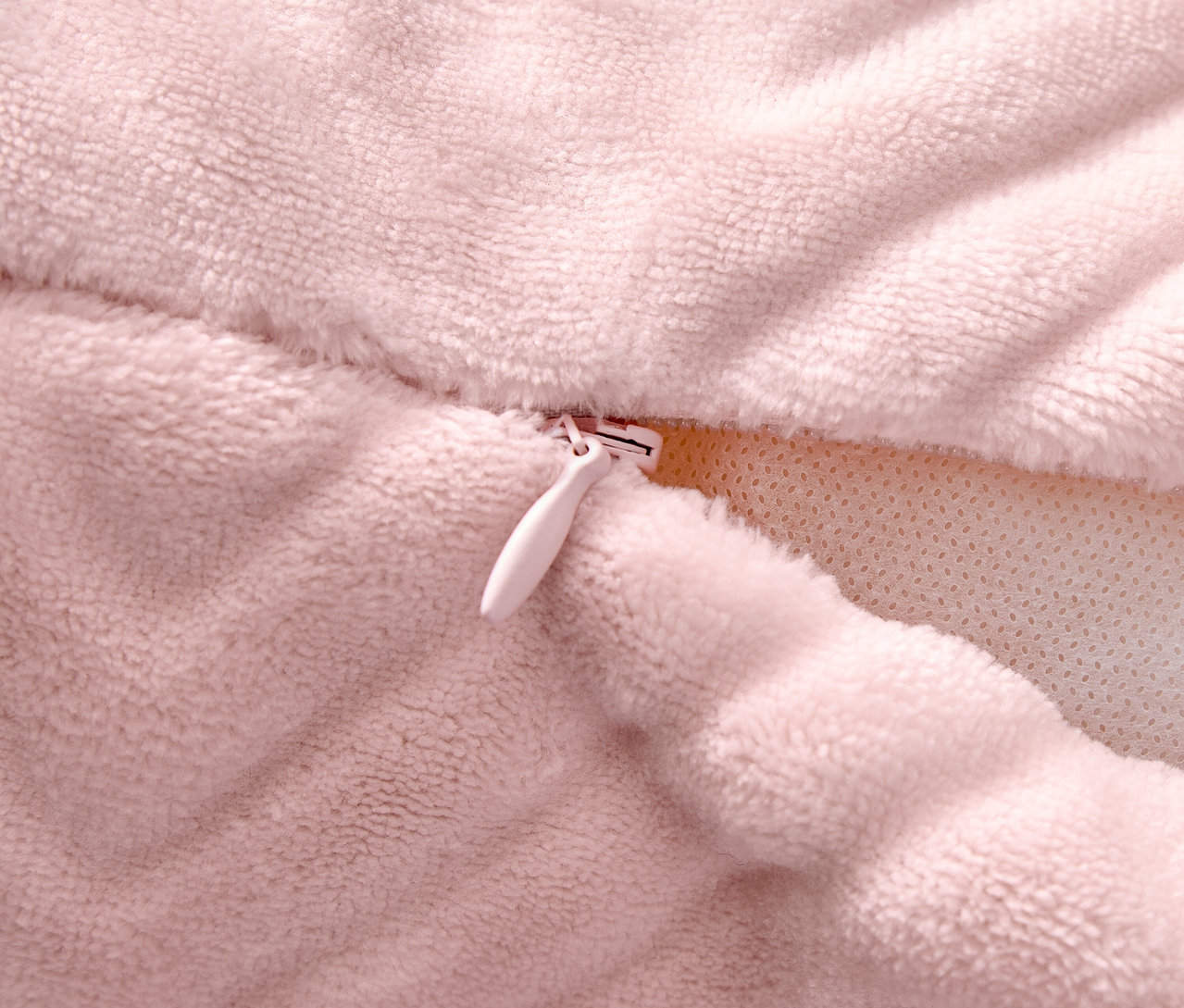 Detailaufnahme eines rosafarbenen Kissenbezugs mit Reißverschluss.