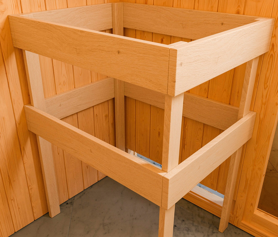 Rahmen von Karibu Saunahaus-Set »Rahlau A« steht in einer Ecke eines Raumes mit Holzvertäfelung.