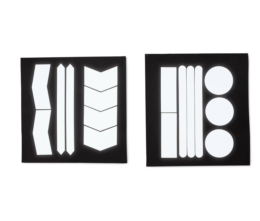 Zwei schwarze Bögen mit reflektierenden Aufklebern in verschiedenen Formen: Streifen, Pfeile und Kreise.