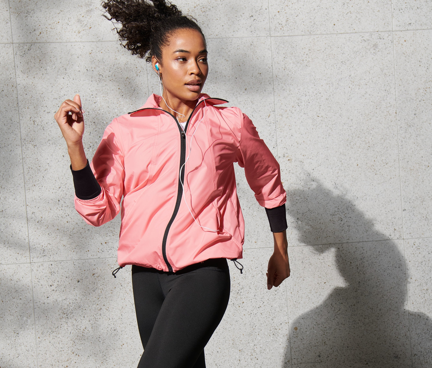Frau mit Laufjacke läuft draussen.