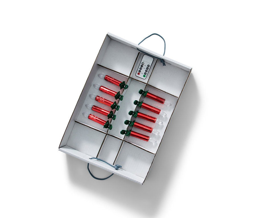 Offene Weihnachtsdeko-Ordnungsbox mit roten Kerzen und Fernbedienung darin.