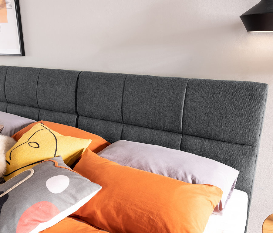Nahaufnahme eines dunkelgrauen Familienbettes, ca. 240 x 200, mit bunten Kissen.