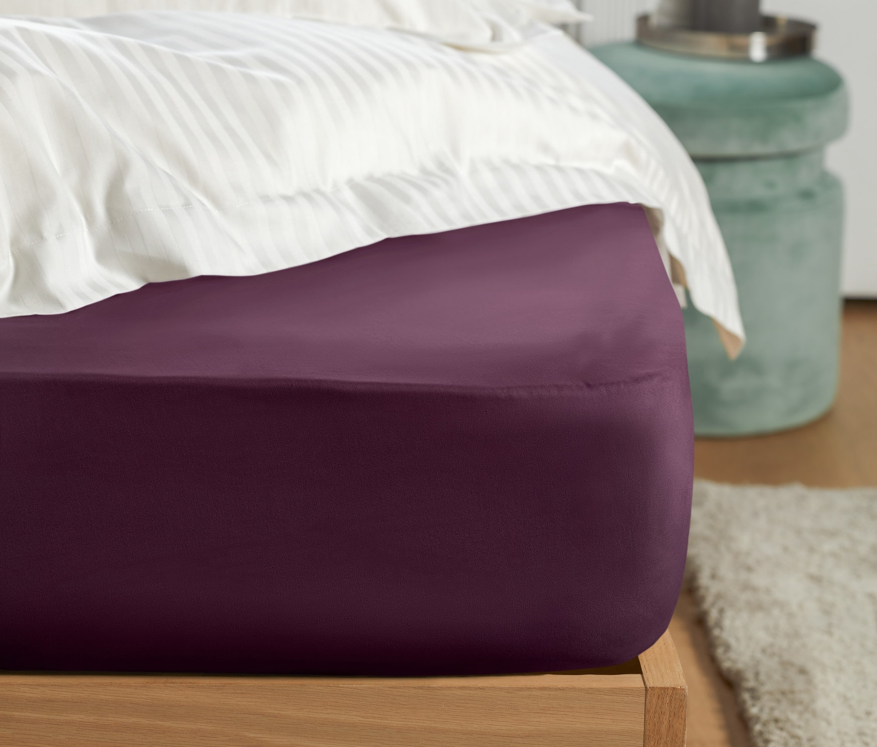 Detailaufnahme eines Bettes mit einem lila Jersey-Spannbettlaken.