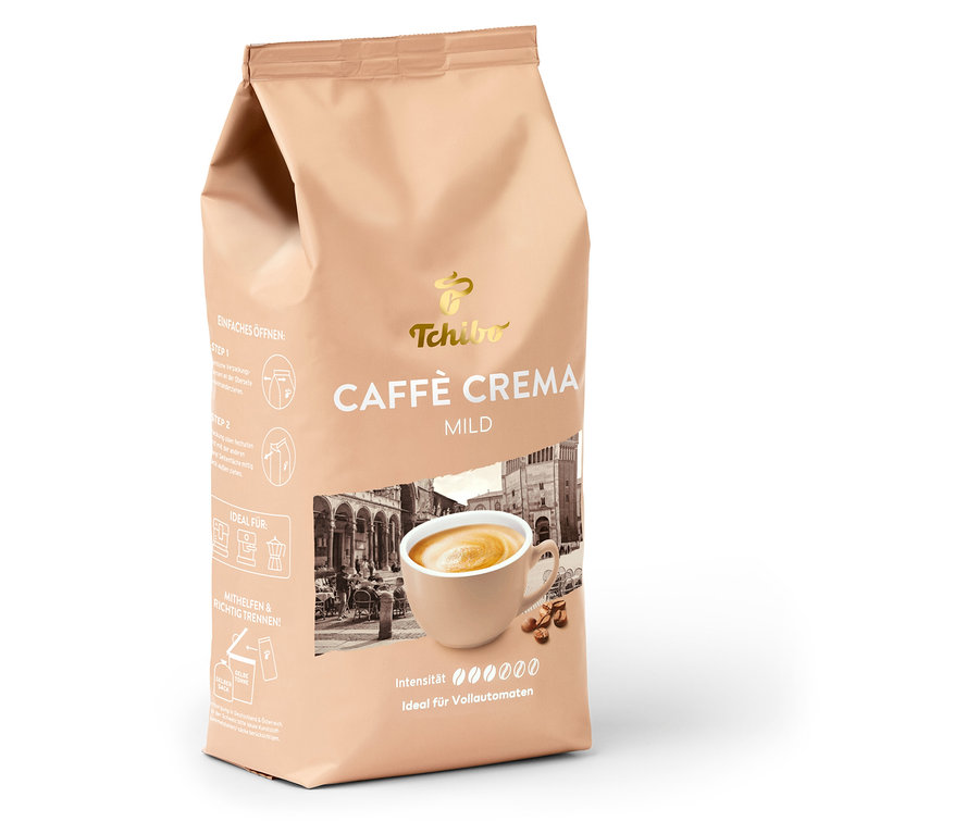Eine hellbraune Packung Tchibo Caffè Crema Mild, 1 kg ganze Bohne, mit einer Tasse Kaffee, Kaffeebohnen und einer verschwommenen Stadtszene. Die Packung weist auf milde Intensität und Eignung für Vollautomaten hin.