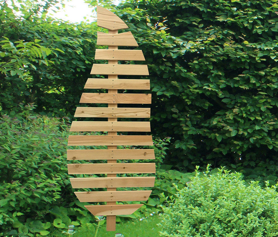 Eine Rankhilfe »Magnolia« steht im Garten zwischen grünen Büschen und roten Blumen.