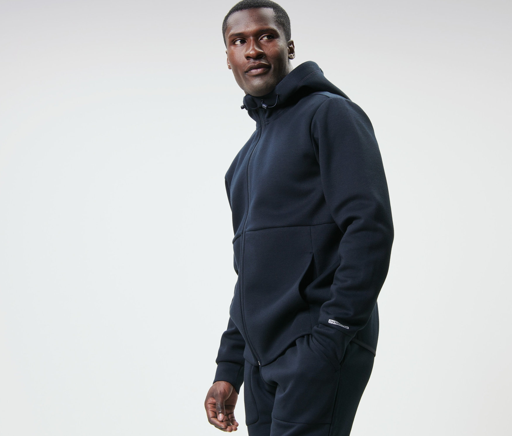 Mann in dunkelblauer Funktionssweatjacke blickt nach links.