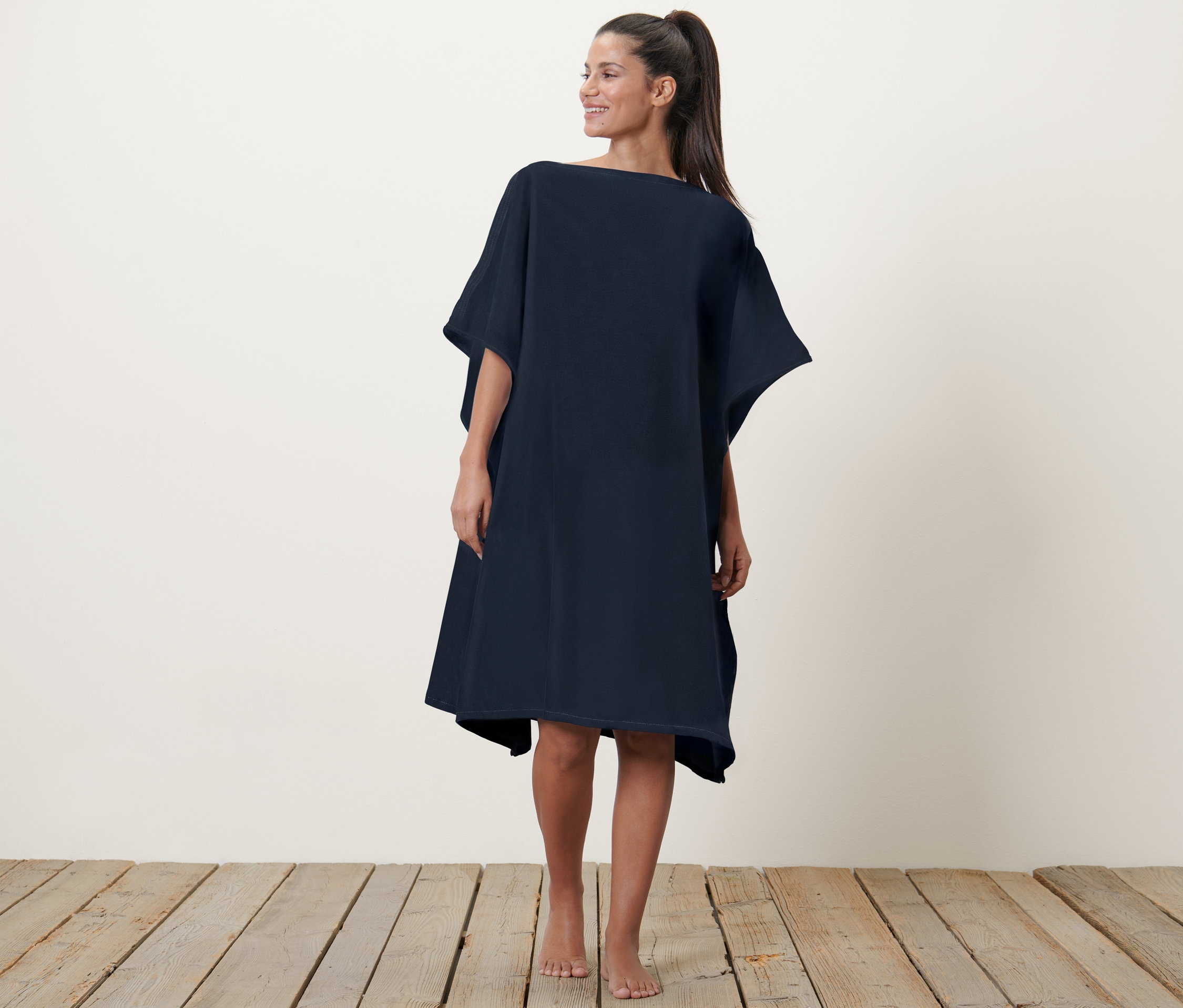 Frau posiert in einem 2-in-1-Badetuch-und-Poncho.