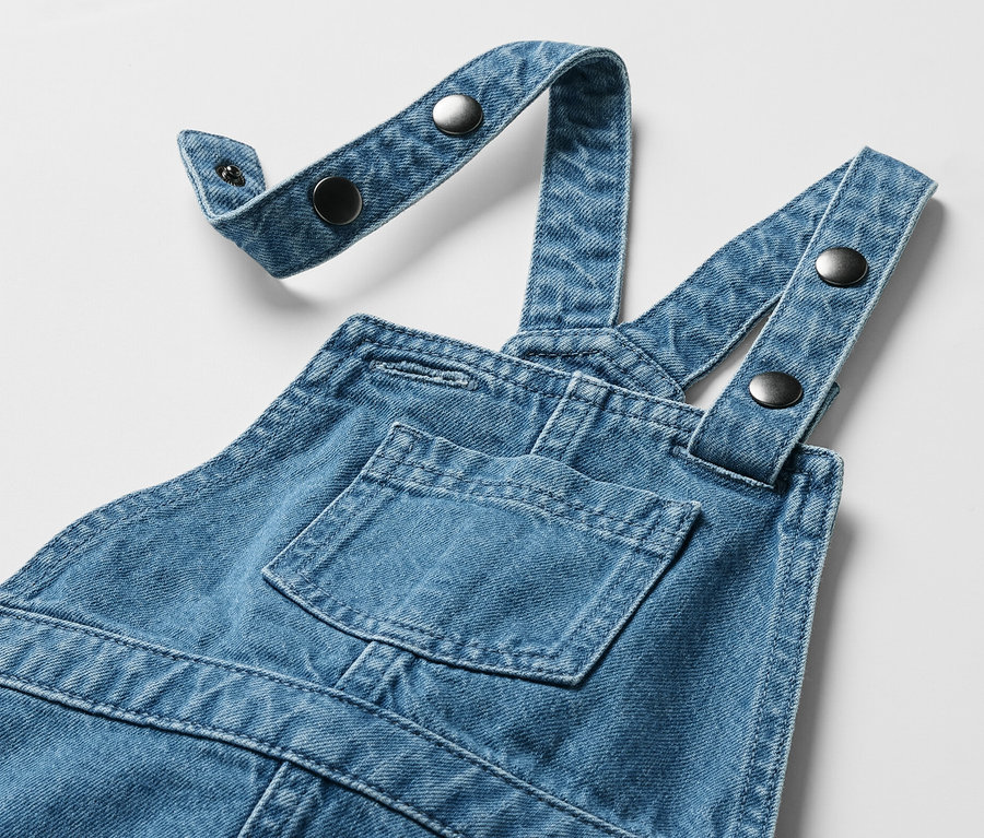 Kinder-Latzkleid mit Brusttasche und verstellbaren Trägern mit Knöpfen.