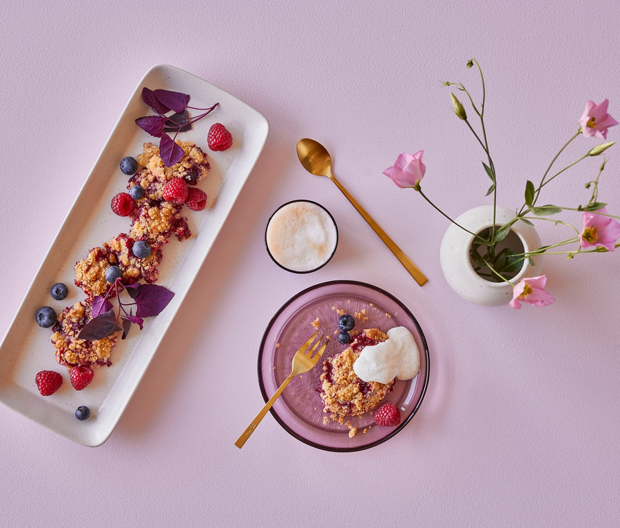 Dessert mit Früchten auf Tellern und rosa Blumen in einer Vase. Auf einem Teller liegt ein 2 Bitz Glasteller »Kusintha«, 18 cm, rosé.
