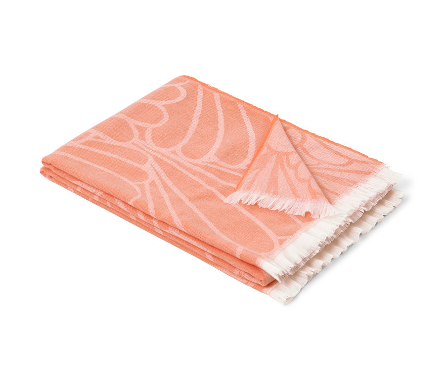 Gefaltete Wende-Wohndecke mit Fransen und orangefarbenem Blumenmuster.