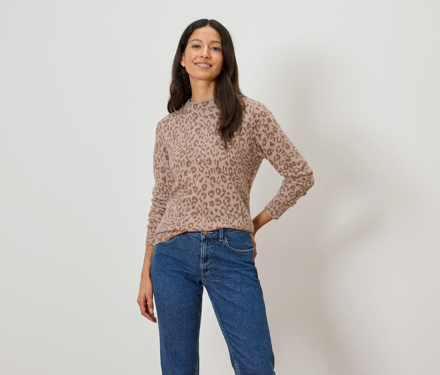 Frau trägt einen hellbraunen Pullover mit Leopardenmuster und blaue Jeans.