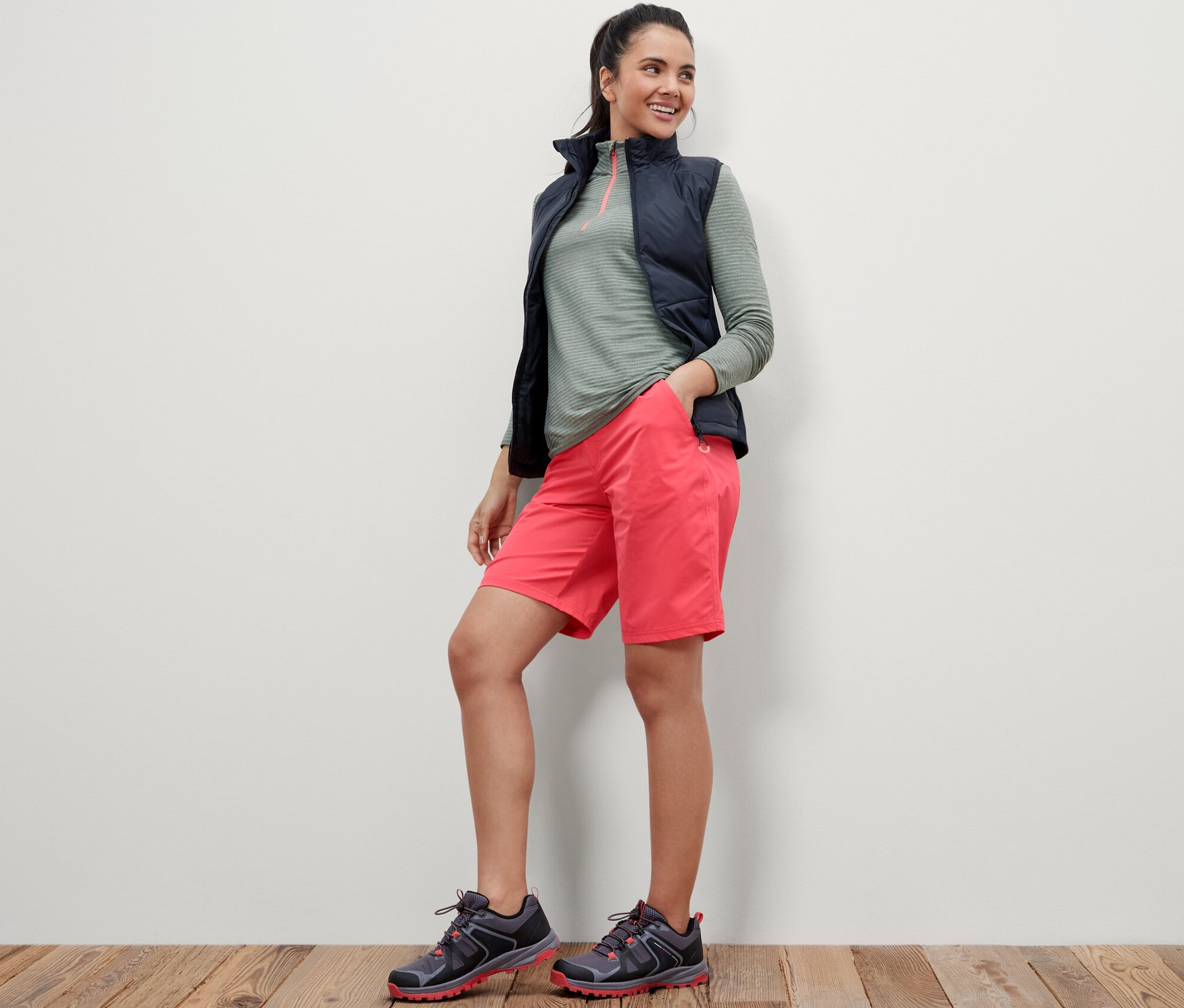 Frau steht mit Händen in den Taschen der pinkfarbenen Softshell-Funktionsshorts.