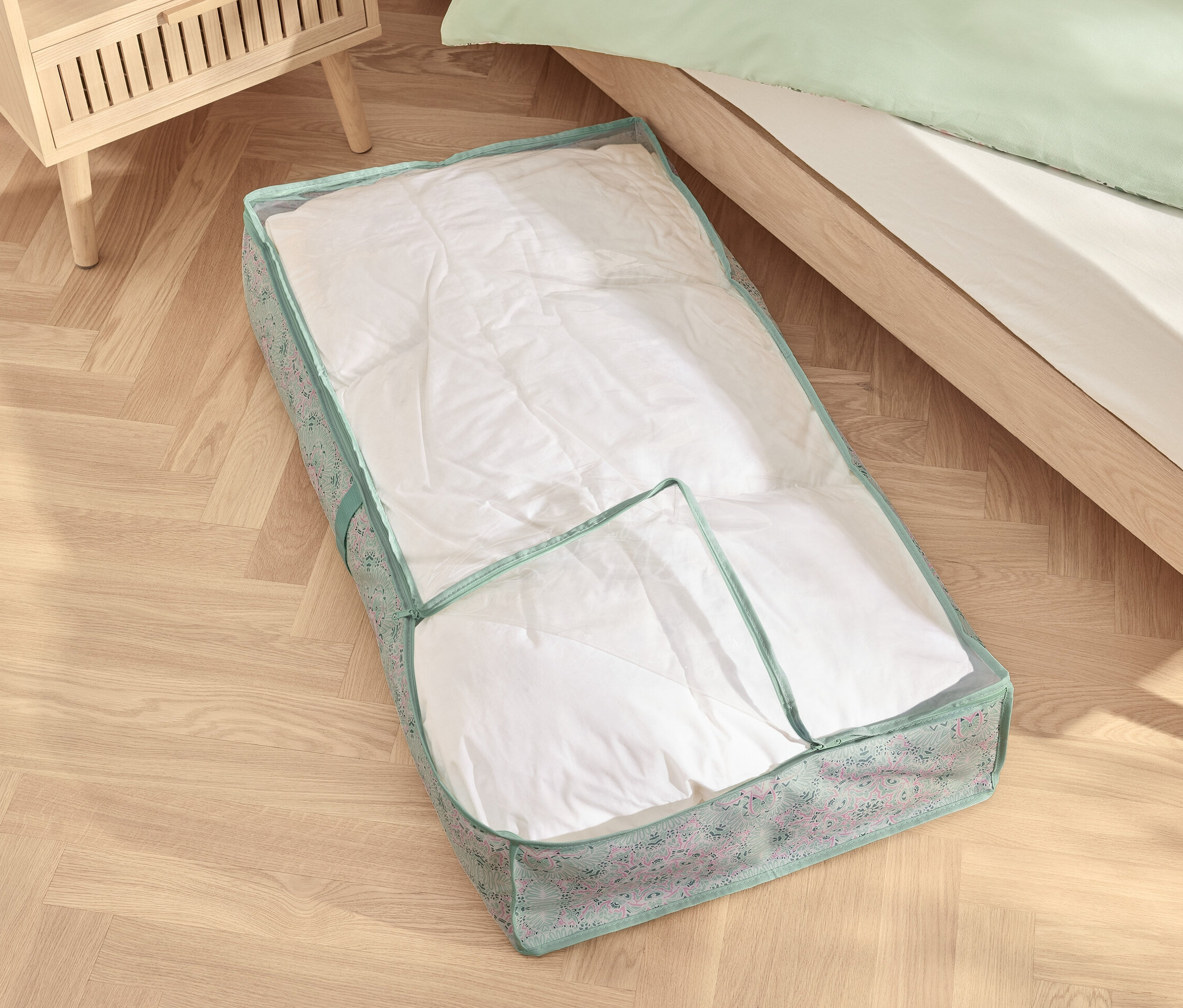 Eine Unterbettkommode mit einer weißen Bettdecke liegt unter dem Bett.