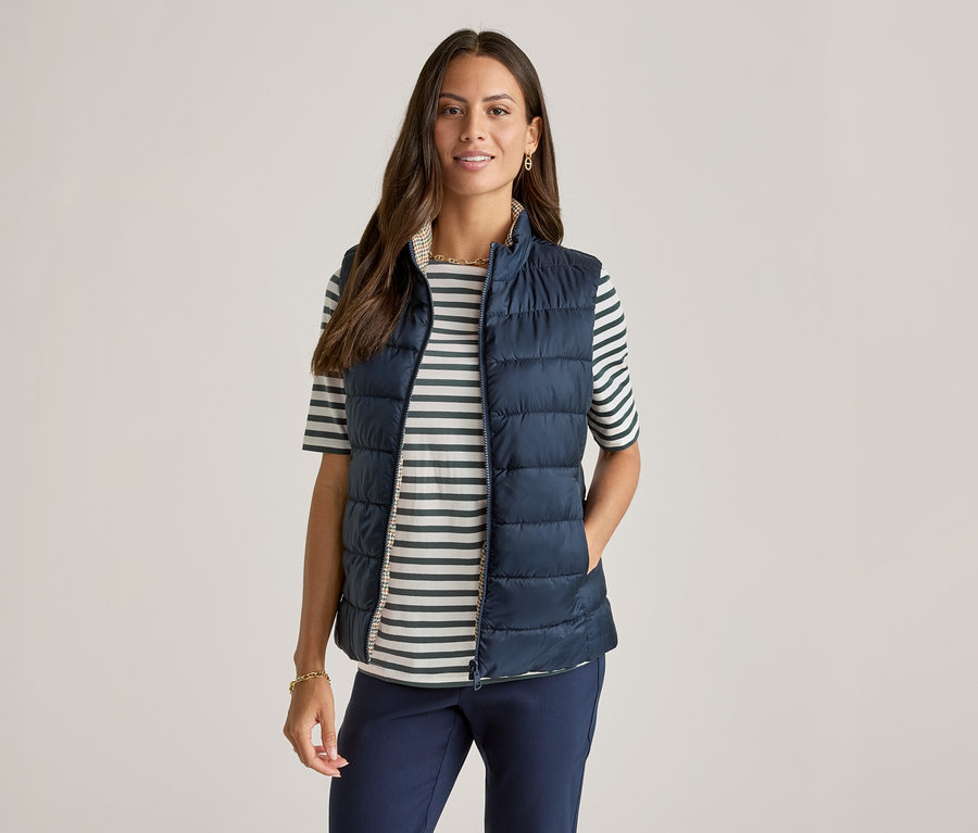 Frau mit marineblauer Weste über einem grün gestreiften Halbarmshirt.