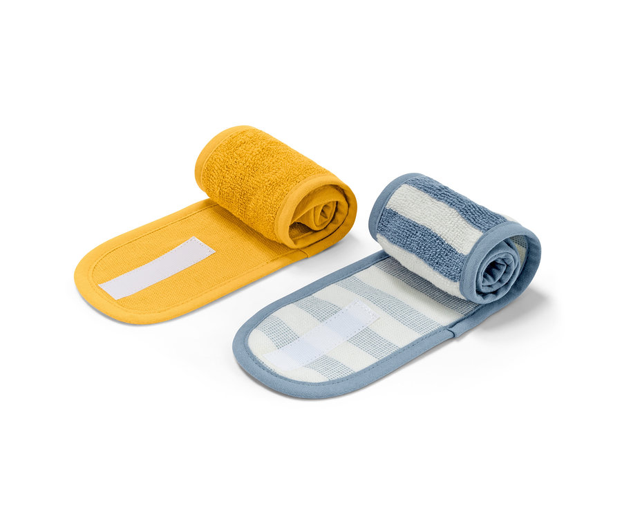 Zwei Kosmetik-Stirnbänder, gelb und weiß-blau gestreift, aufgerollt auf weißem Hintergrund.