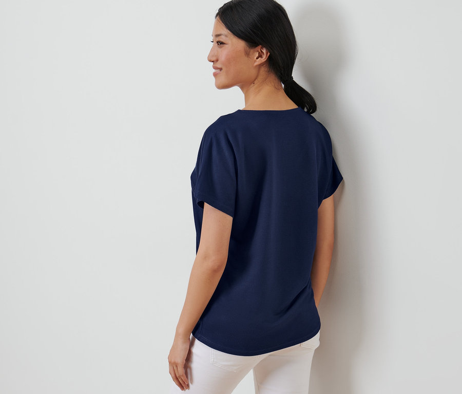 Frau posiert in einem dunkelblauen, strukturierten Shirt.