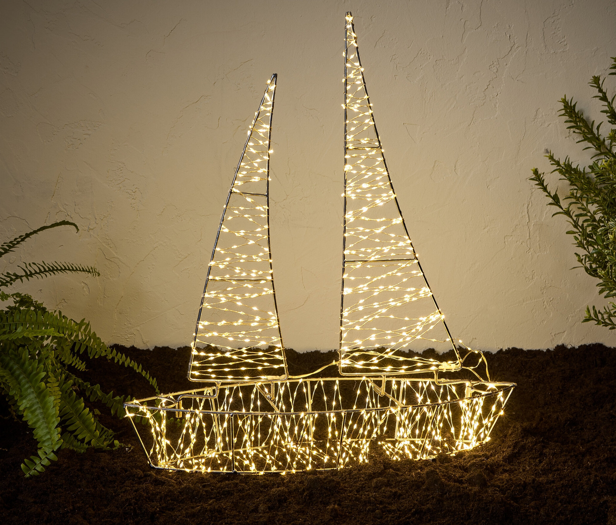 Ein beleuchtetes LED-3D-Outdoor-Boot steht neben Pflanzen auf dem Boden.