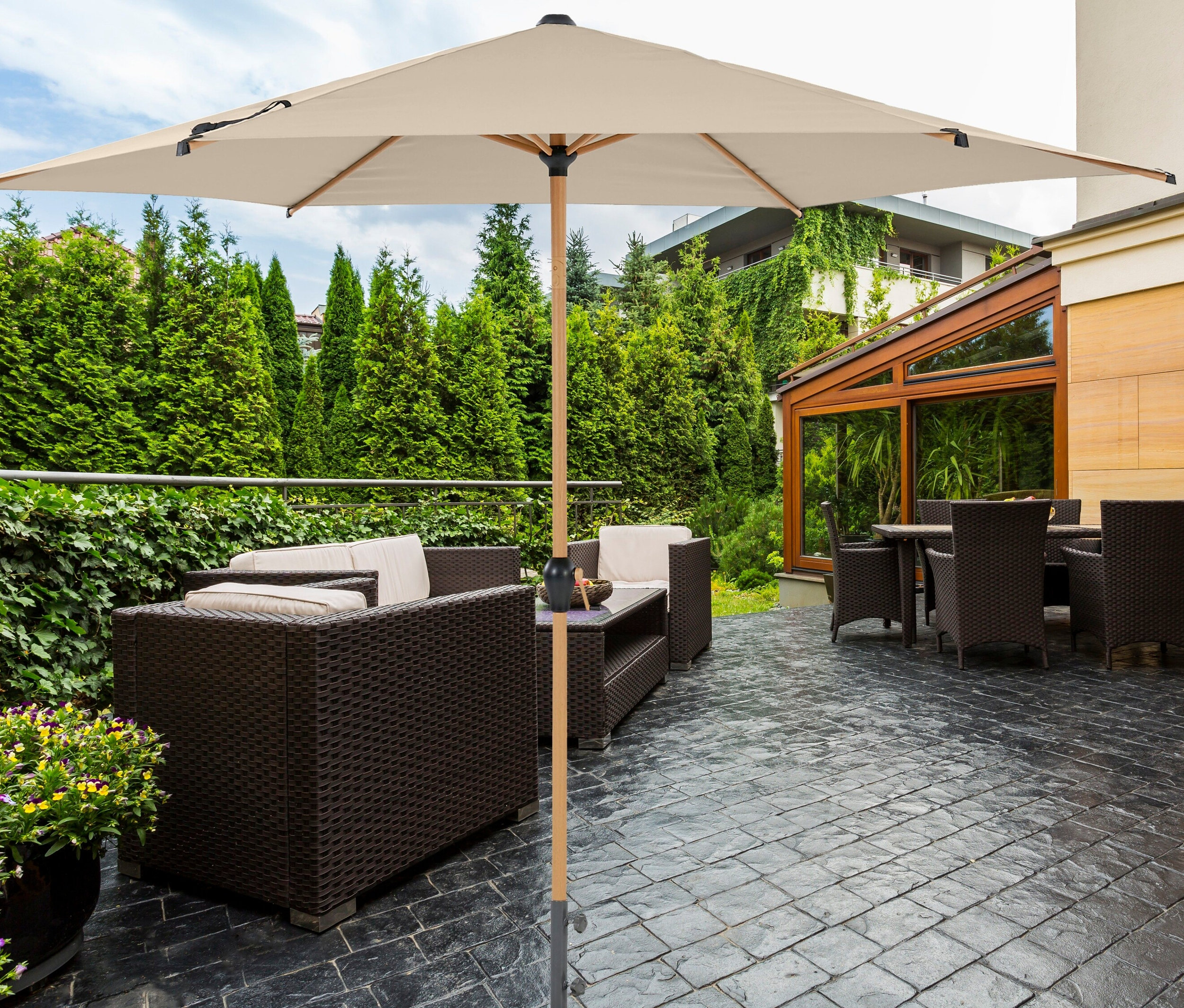 Terrasse mit beigem Leco Marktschirm in Holzoptik und braunen Korbmöbeln.