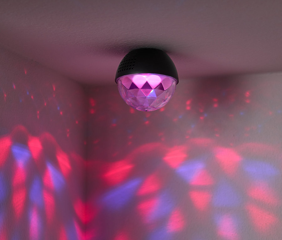 Eine Diskokugel ist an der Decke befestigt und wirft rote und blaue Lichter an die Wände des Raumes.