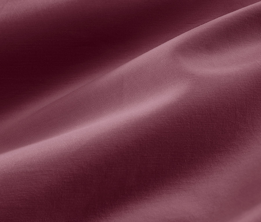 Nahaufnahme der Textur von beerefarbener Baumwollsatin-Bettwäsche in Übergröße.