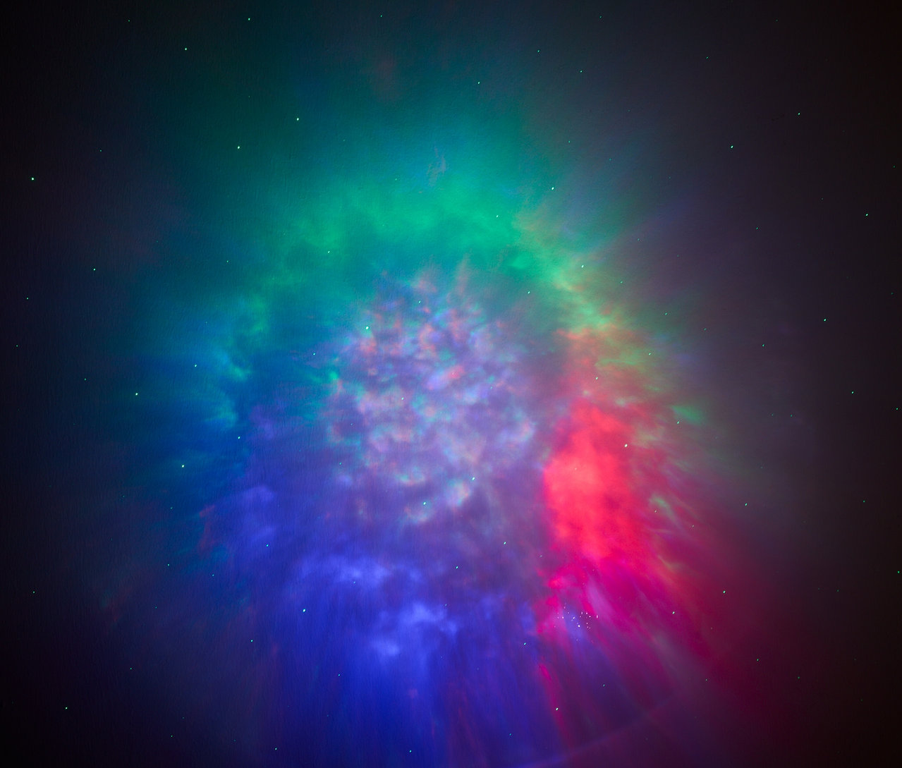 Ein Nebel mit Schattierungen von Grün, Rot und Blau vor einem dunklen Hintergrund.