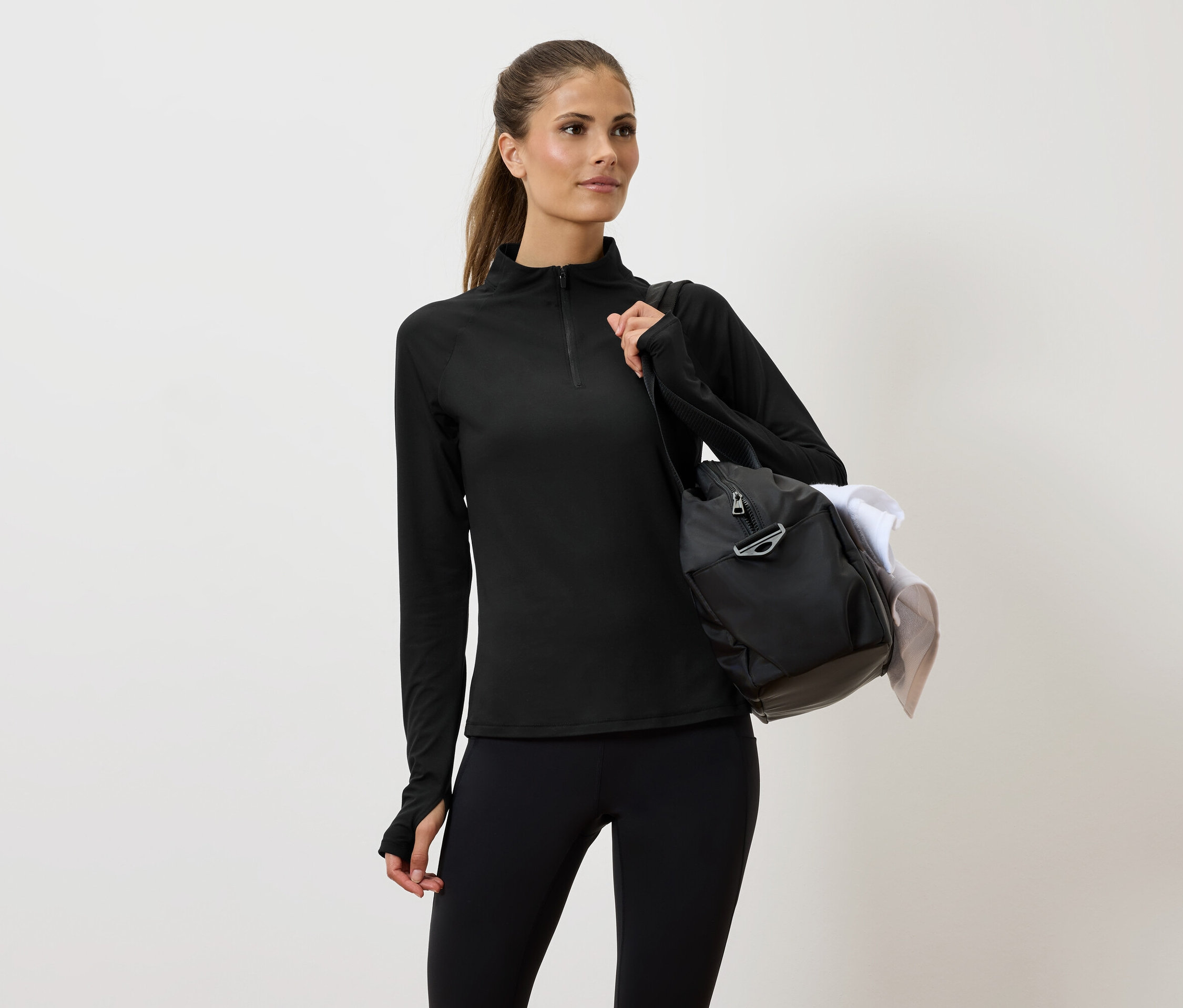 Frau in schwarzer Sportbekleidung mit einer Tasche über der Schulter.
