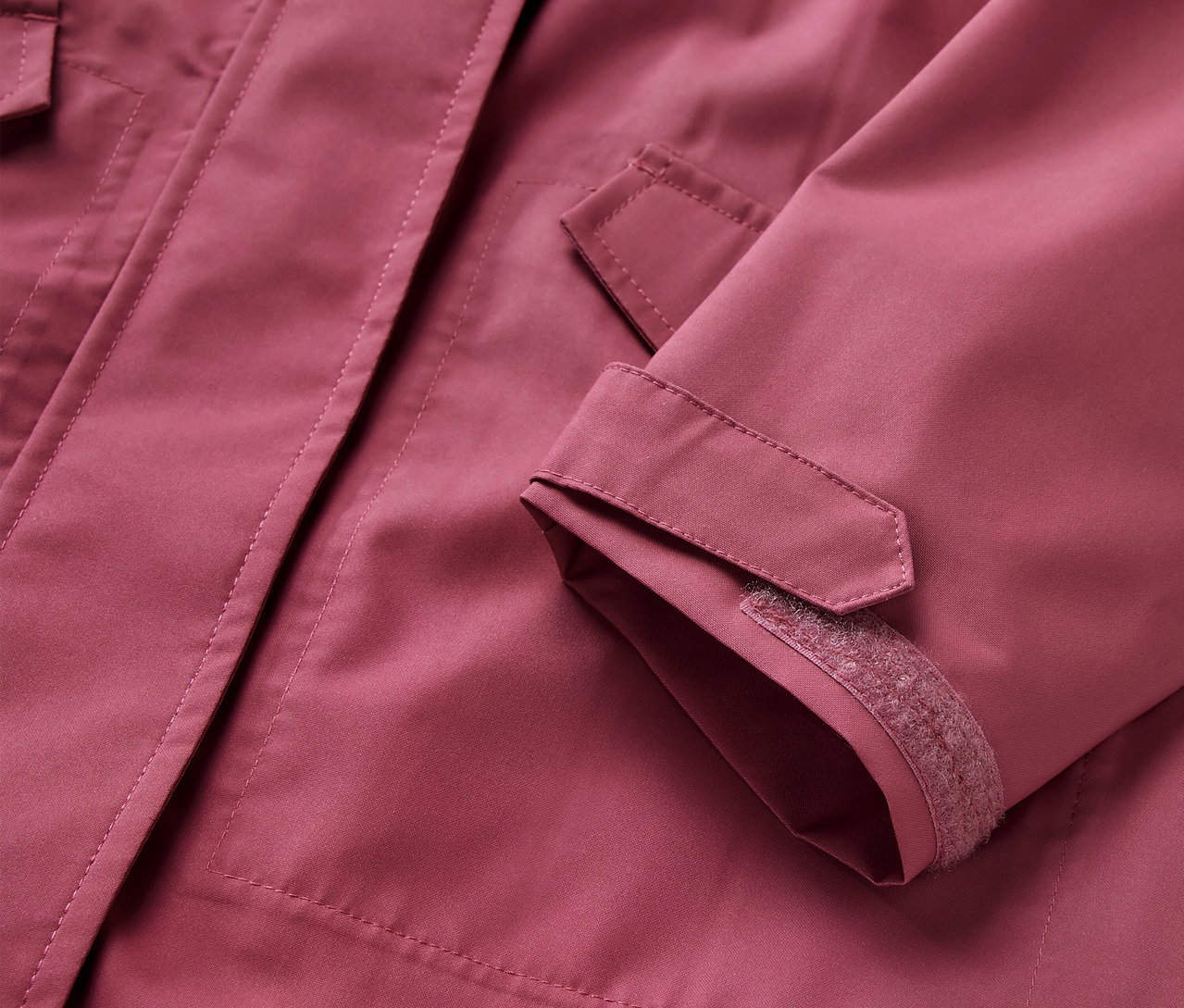 Detailansicht eines Kinder-Regenparkas, rosa Jacke mit Taschen und verstellbaren Ärmelbündchen.