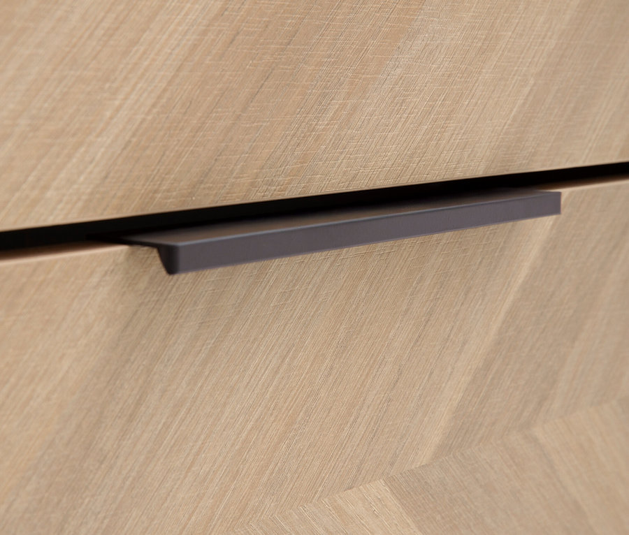 Nahaufnahme eines hellbraunen Holzschubladenelements mit einem horizontalen grauen Griff.