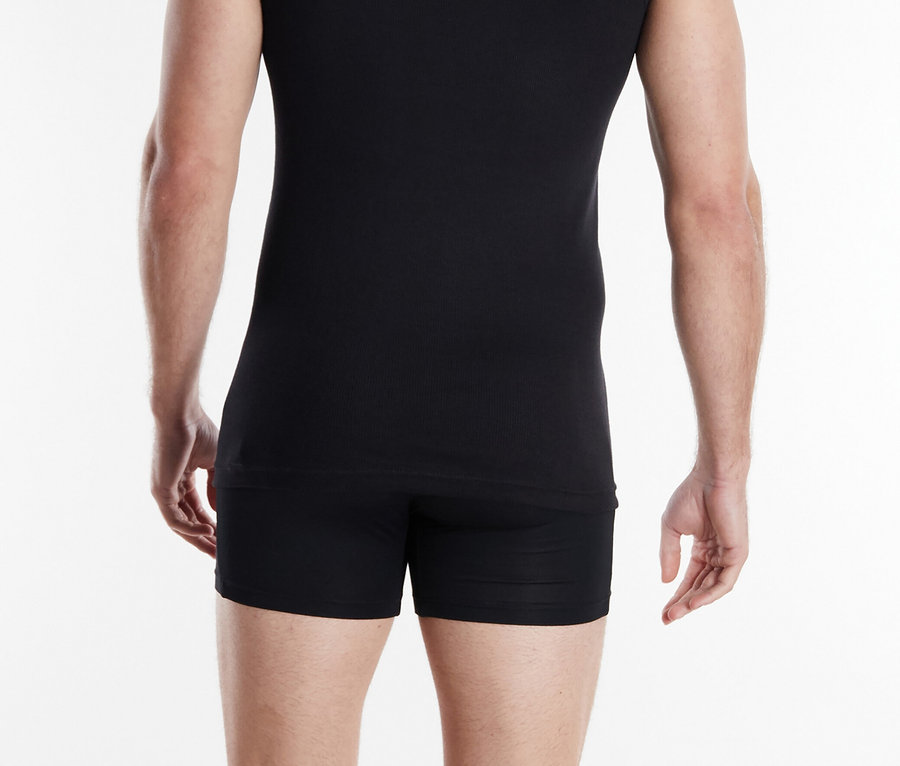 Mann von hinten in schwarzem Unterhemd und Shorts vor weißem Hintergrund.