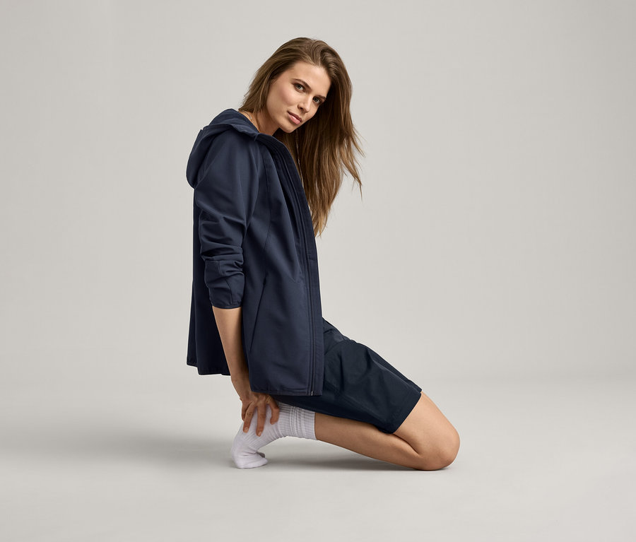 Frau kniet und trägt eine marineblaue Jacke und Shorts.