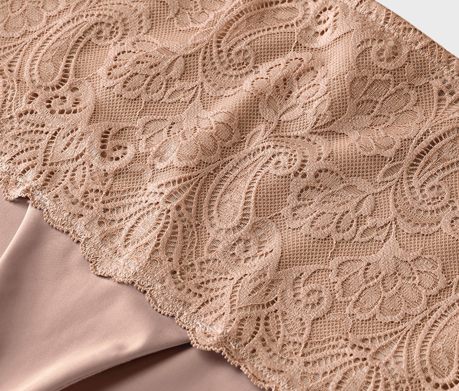 Nahaufnahme von beigem Stoff mit floraler Spitze.