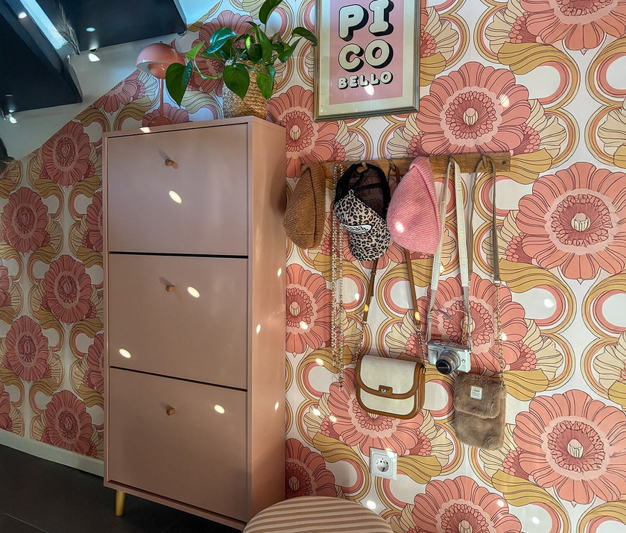 Aprikosenfarbener Schuhschrank »Bjarne« mit drei Klappen steht vor einer floralen Tapete.