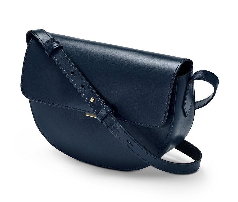 Eine dunkelblaue Lederhandtasche »Saddle Bag« auf weißem Hintergrund.