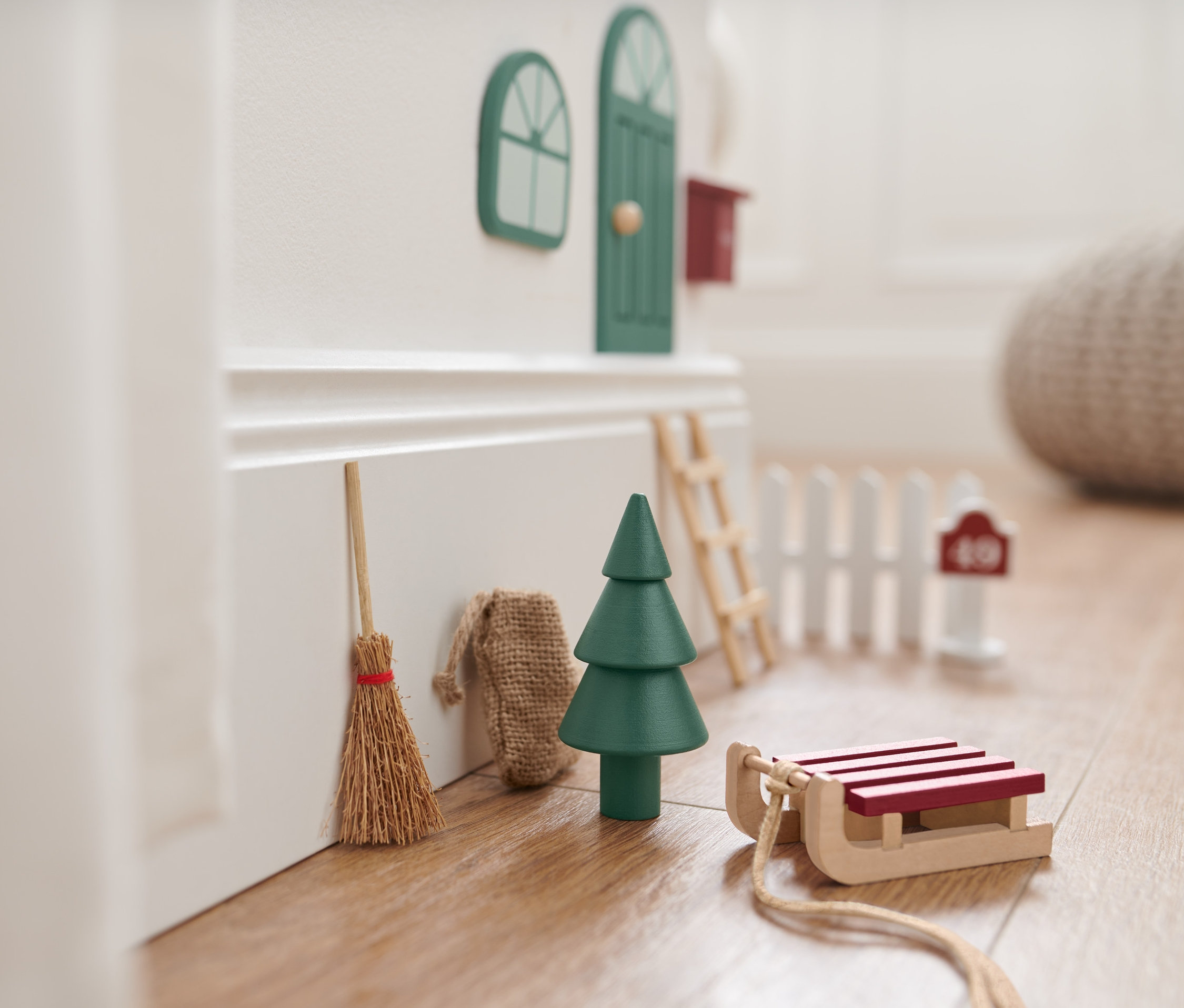 Dekorative Wichteltür-Accessoires an einer Wand, inklusive Besen, Baum, Schlitten und Leiter.