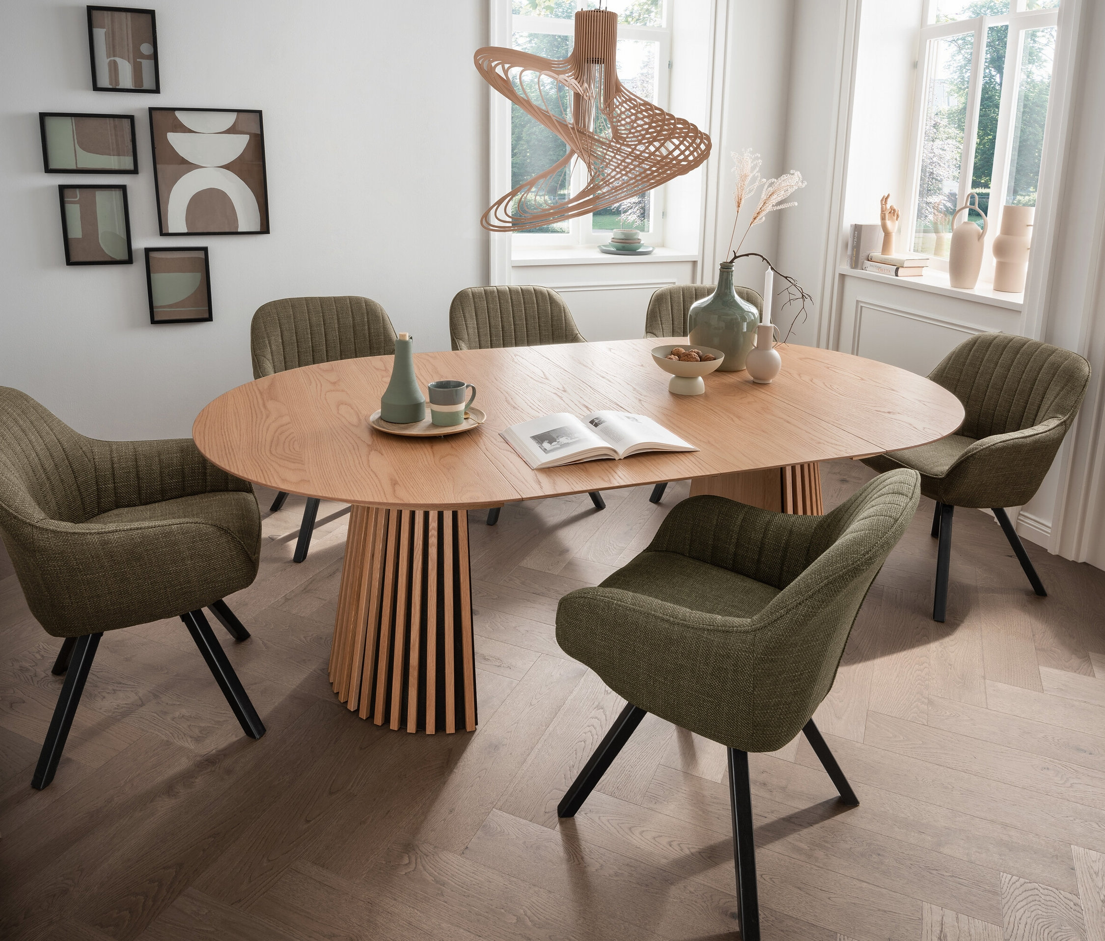 Ovaler Holztisch umgeben von sechs grünen deVries Diningsesseln »Matera«.