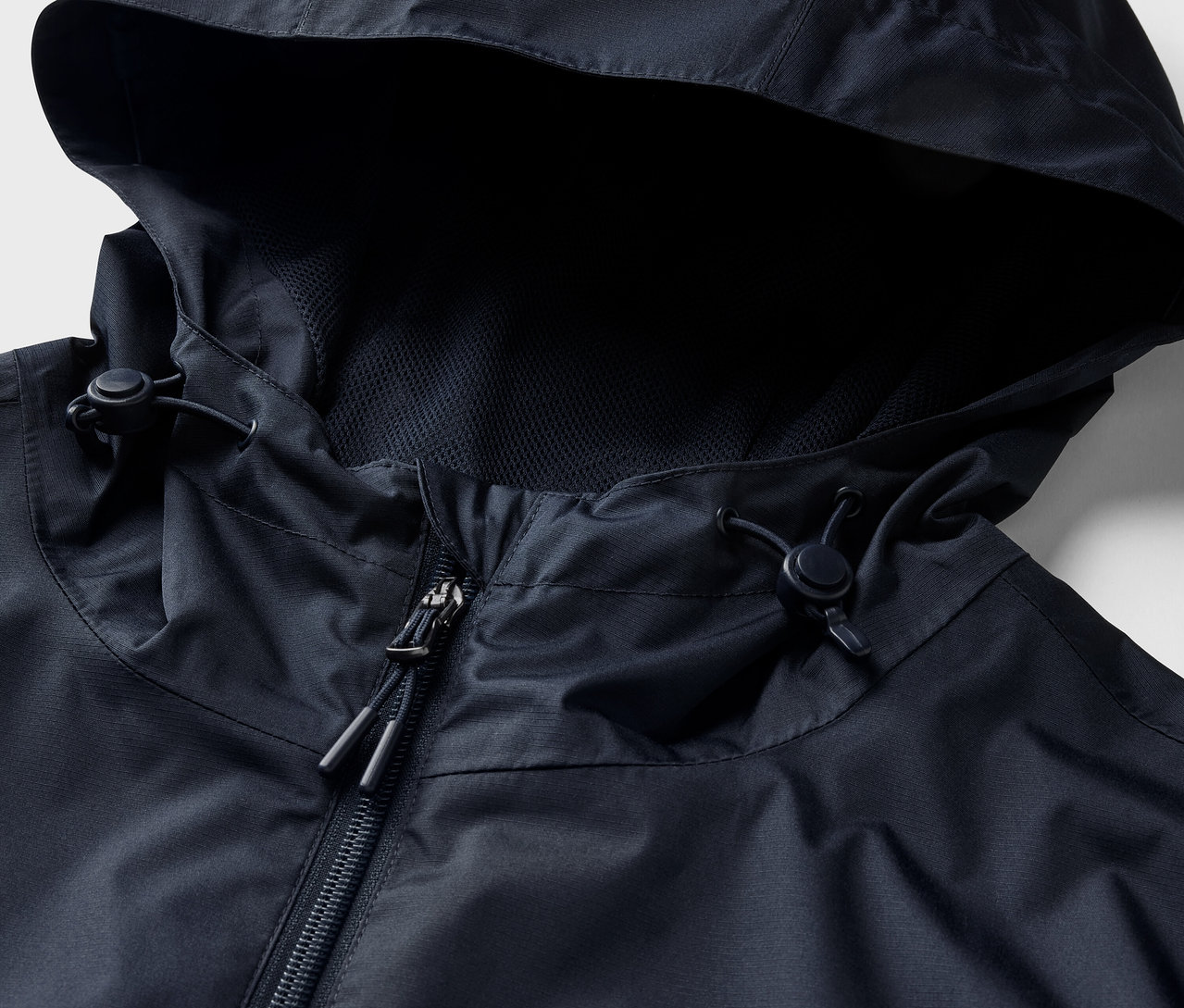 Detailansicht einer marineblauen Regenjacke mit Kapuze und Reißverschluss.