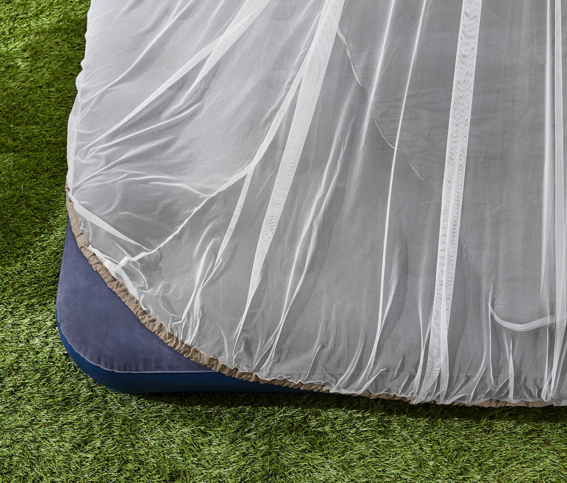 Ein Reise-Moskitonetz liegt auf einer Matratze im Gras.