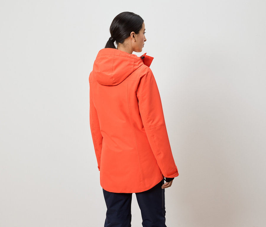 Frau mit dem Rücken zur Kamera trägt eine orangefarbene Jacke mit Kapuze.