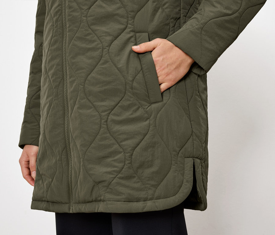 Detailaufnahme einer olivgrünen Steppjacke mit einer Hand in der Tasche.
