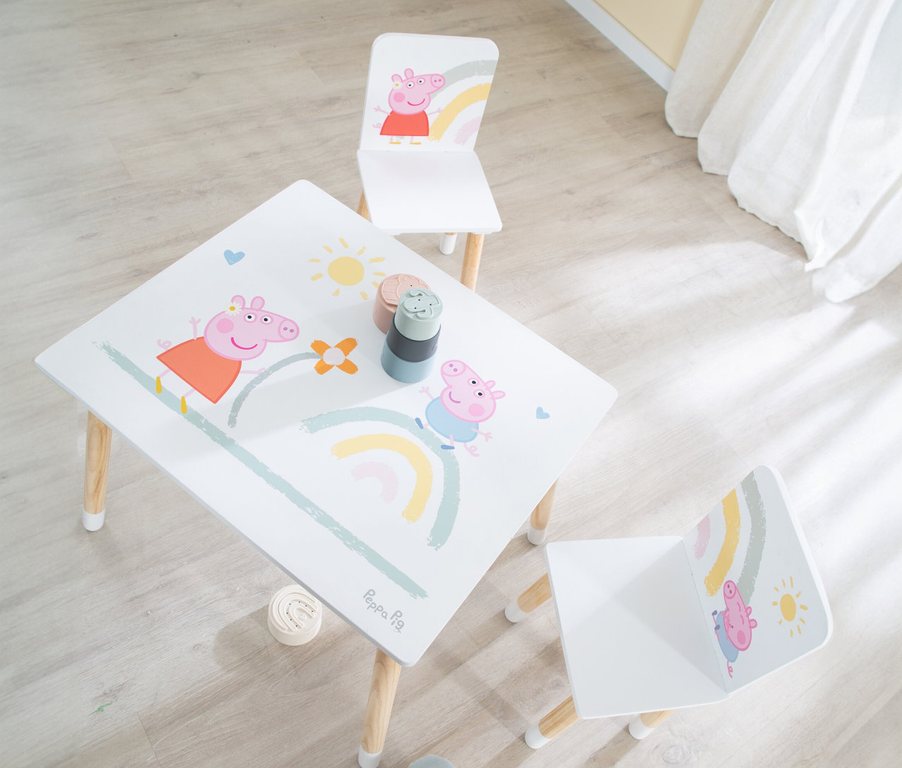 Draufsicht auf einen Kindertisch mit Peppa Wutz-Motiv und zwei Stühlen mit Holzbeinen.