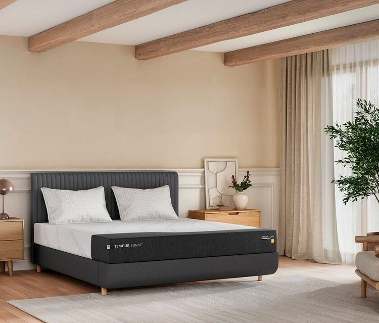 Schlafzimmer mit Tempur Form Matratze auf einem grauen Bettgestell mit Kopfteil, zwei Kissen und zwei Nachttischen.