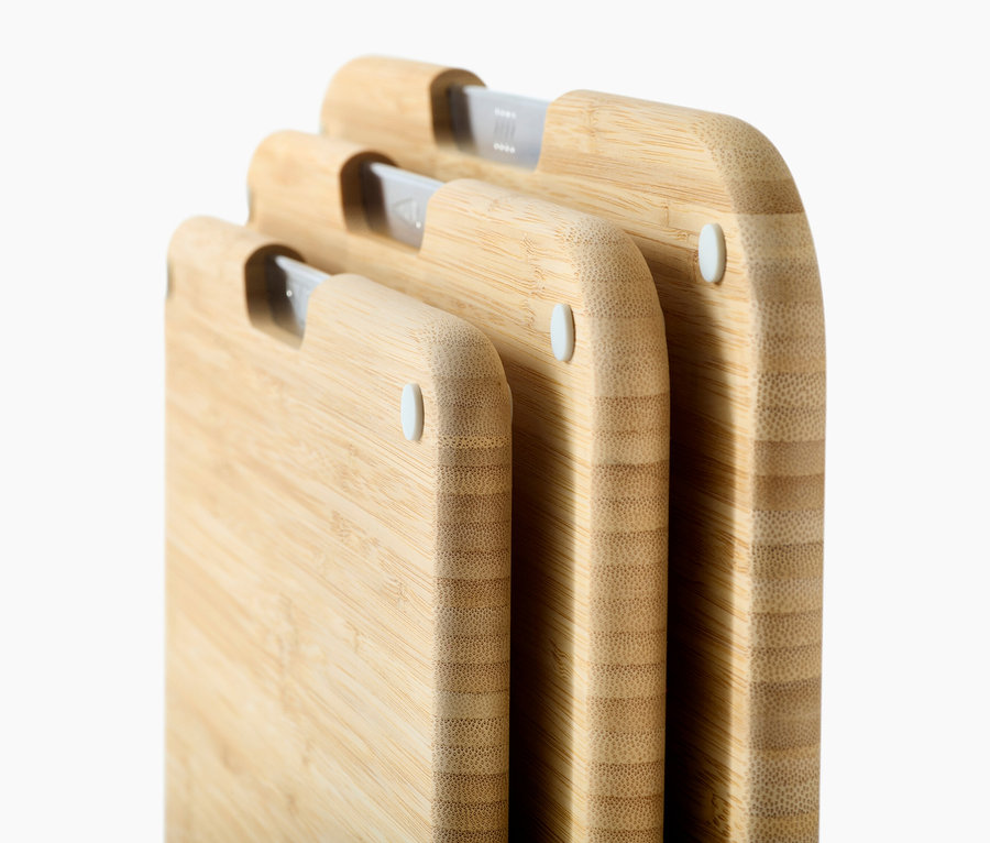 Drei helle Schneidebretter aus Holz stehen gestapelt übereinander.