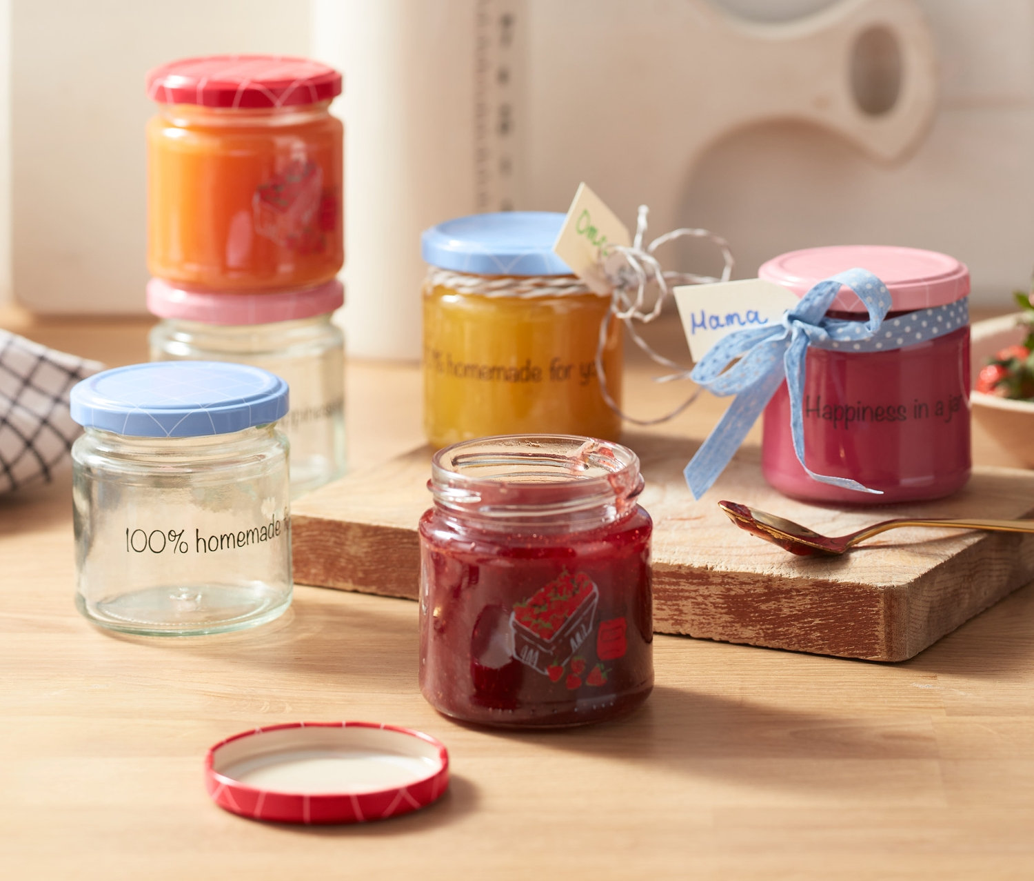 Sechs Gläser mit Schraubverschluss mit selbstgemachten Marmeladen und Etiketten auf einem Holztisch.