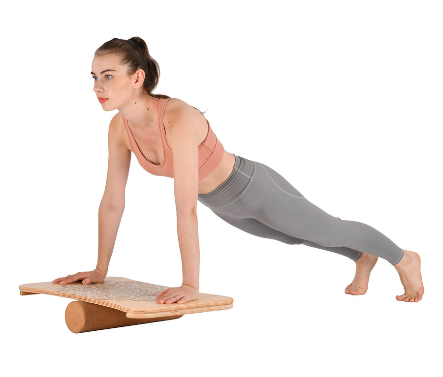 Frau macht Plank auf Balance-Board.