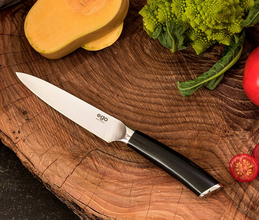 Auf einem Holzbrett liegen geschnittener Kürbis, Romanesco, Tomaten und ein WILFA Universalmesser EGO Sandvik »ES13UK«.