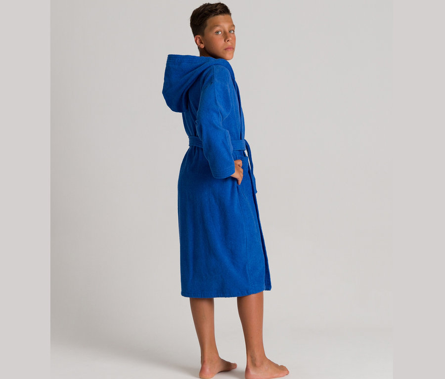 Ein Junge schaut über die Schulter, er trägt einen blauen Bademantel mit Kapuze.