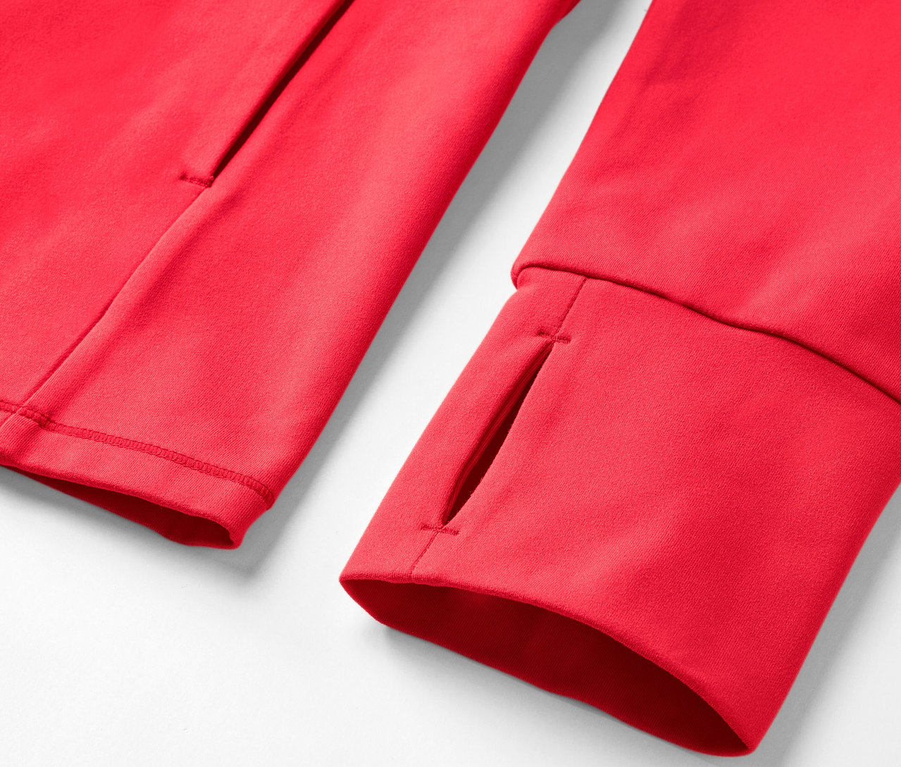 Detailaufnahme einer roten Trainingsjacke mit Daumenloch und Tasche.